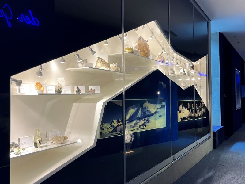 Große, lichtdurchlässige Kristalle, die in einer musealen Umgebung ausgestellt und beleuchtet werden, um ihre facettierten Oberflächen und natürlichen Strukturen hervorzuheben.