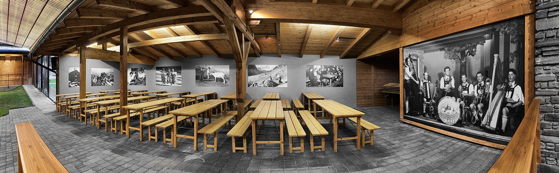 Ein geräumiger hölzerner Essbereich mit langen Bänken und historischen Schwarz-Weiß-Fotografien an den Wänden.